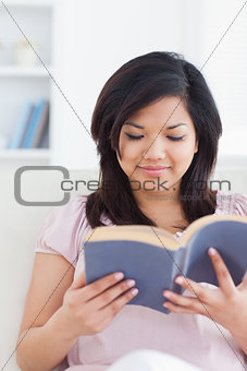 Woman sits on a couch while reading a book