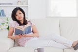 Woman lying on a couch while holding a book