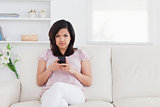 Woman sitting on a couch while holding a phone