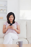 Woman sitting on a sofa while she is holding a phone