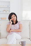 Smiling woman phoning while sitting on a couch