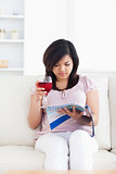 Woman sits on a couch and holds a magazine