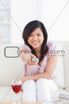 Blurred woman holding a television remote while sitting on a cou