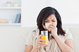 Sneezing woman drinking a glass of orange juice