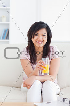 Smiling woman sitting and holding a glass of orange juice