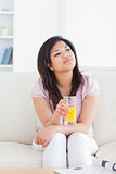Woman sitting on a couch while holding a glass of orange juice