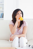 Woman sitting on a couch while drinking a glass of orange juice