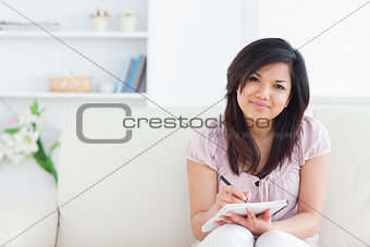 Woman smiling while writing on a notebook