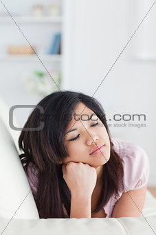Woman lying on a sofa while holding her head