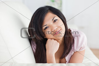 Woman resting on a sofa while holding her head with her fist