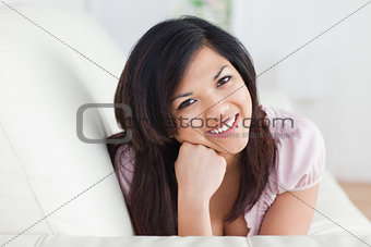 Smiling woman relaxing on a couch while holding her head with he