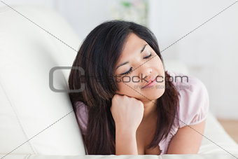 Woman closing her eyes while resting on a couch