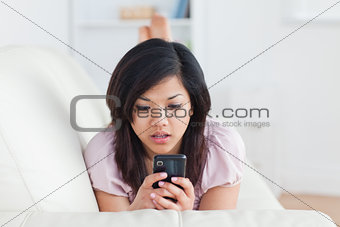 Surprised woman looking at a phone on a sofa