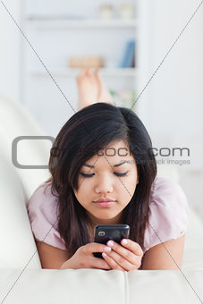 Woman lying on a sofa while looking at a phone