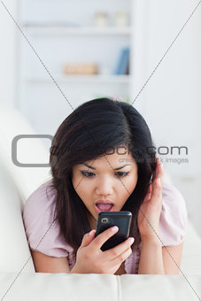 Chocked woman phoning while resting on a sofa