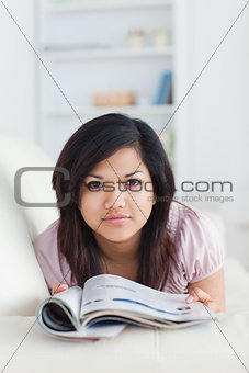 Woman holding a magazine while resting on a couch