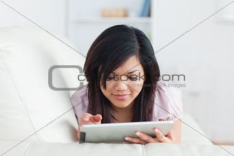 Woman lying on a couch while holding a tablet