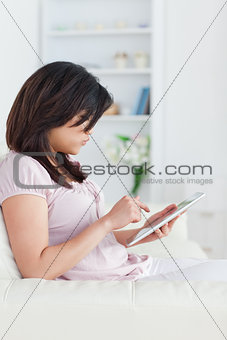 Woman holding a tablet while she sits on a sofa