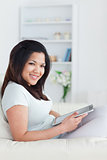 Woman sitting on a couch while holding a tablet