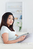Woman sitting on a couch and holding a tablet