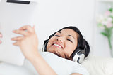 Woman lying on a couch with headphones on and a tactile tablet i