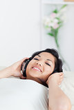 Woman smiling and lying on a sofa with headphones on