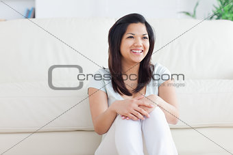 Woman smiles as she sits in front of a couch on the floor