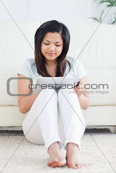 Woman sits on the floor while playing with a tactile tablet