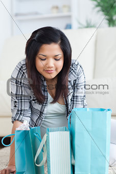 Woman sitting on the floor while looking at shopping bags