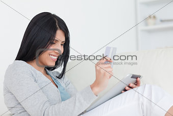 Woman holding up a card and a tablet