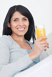 Woman smiling while holding a glass full of orange juice