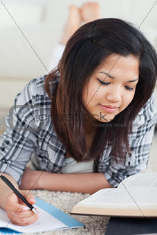 Woman writing on a notebook and reading a book