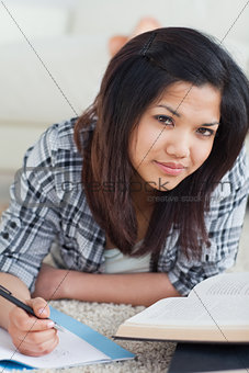 Woman laying on the floor while writing on a notebook