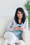 Woman holding a phone while relaxing on a couch