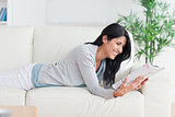 Woman reading a magazine as she lays on a couch