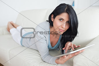 Woman resting on a sofa while touching a tactile tablet