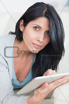 Close up of a woman laying on a couch while typing on a tablet