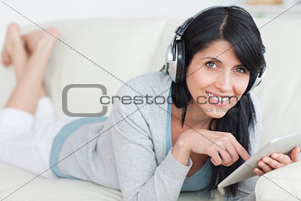 Smiling woman with headphones on while holding a tablet
