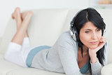 Woman thinking with headphones on while laying on a couch