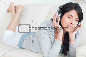 Woman laying on a sofa while wearing headphones