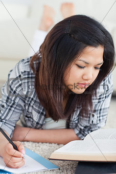 Woman writing on a notebook while she reads a book