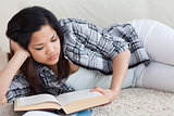 Woman reading a book as she lays on the floor