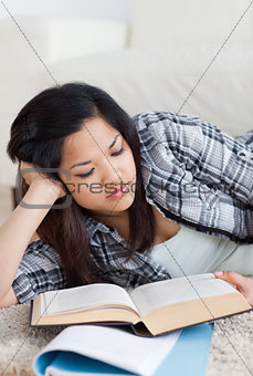 Close-up of a woman reading a book as she lays on the floor