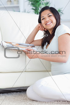Smiling woman on her knees while holding a magazine