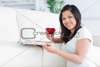 Woman on her knees holding a glass of red wine and a magazine