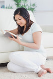 Woman reading a book while she sits on the floor
