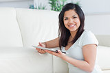 Smiling woman holding a tactile tablet in front of a sofa