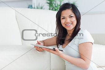 Smiling woman holding a tactile tablet in front of a sofa