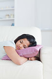 Woman resting on a couch with her head on a pillow