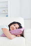 Woman resting her head on a pillow while lying on a couch